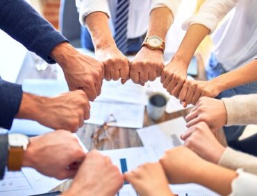Group,Of,Business,Workers,Standing,Bumping,Fists,At,The,Office
